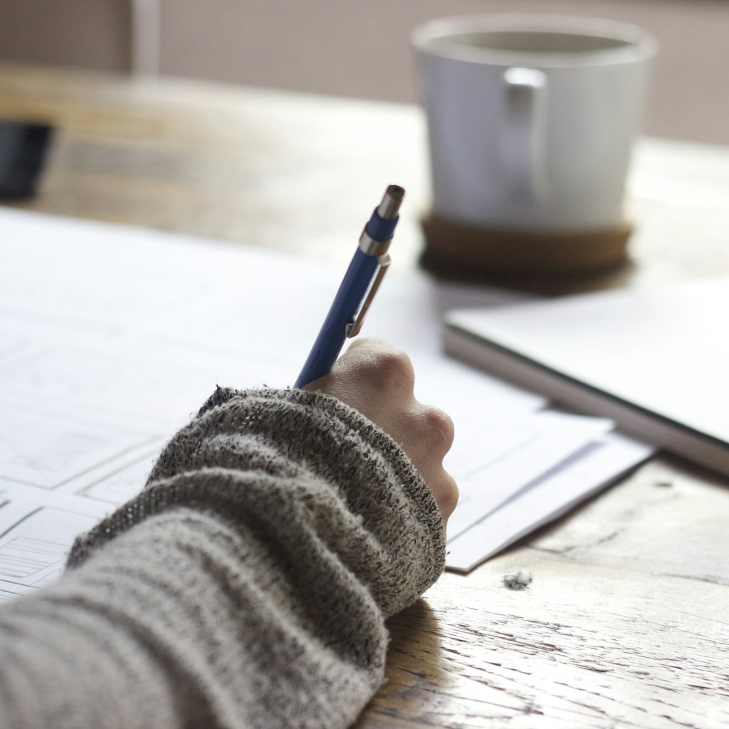 A closed laptop pushed aside next to a blank paper exam on a student desk