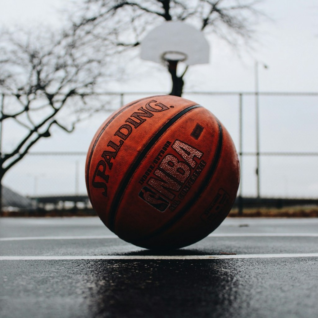 An empty small-town high school gym with the lights on and the bleachers pulled out before a game